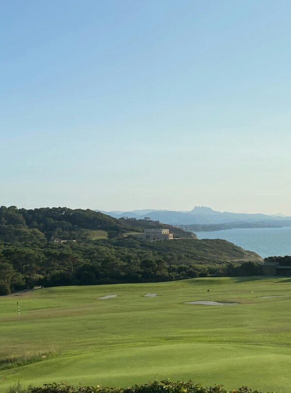 A picturesque view of a golf course by the coast in Biarritz, showcasing lush greenery and serene ocean.