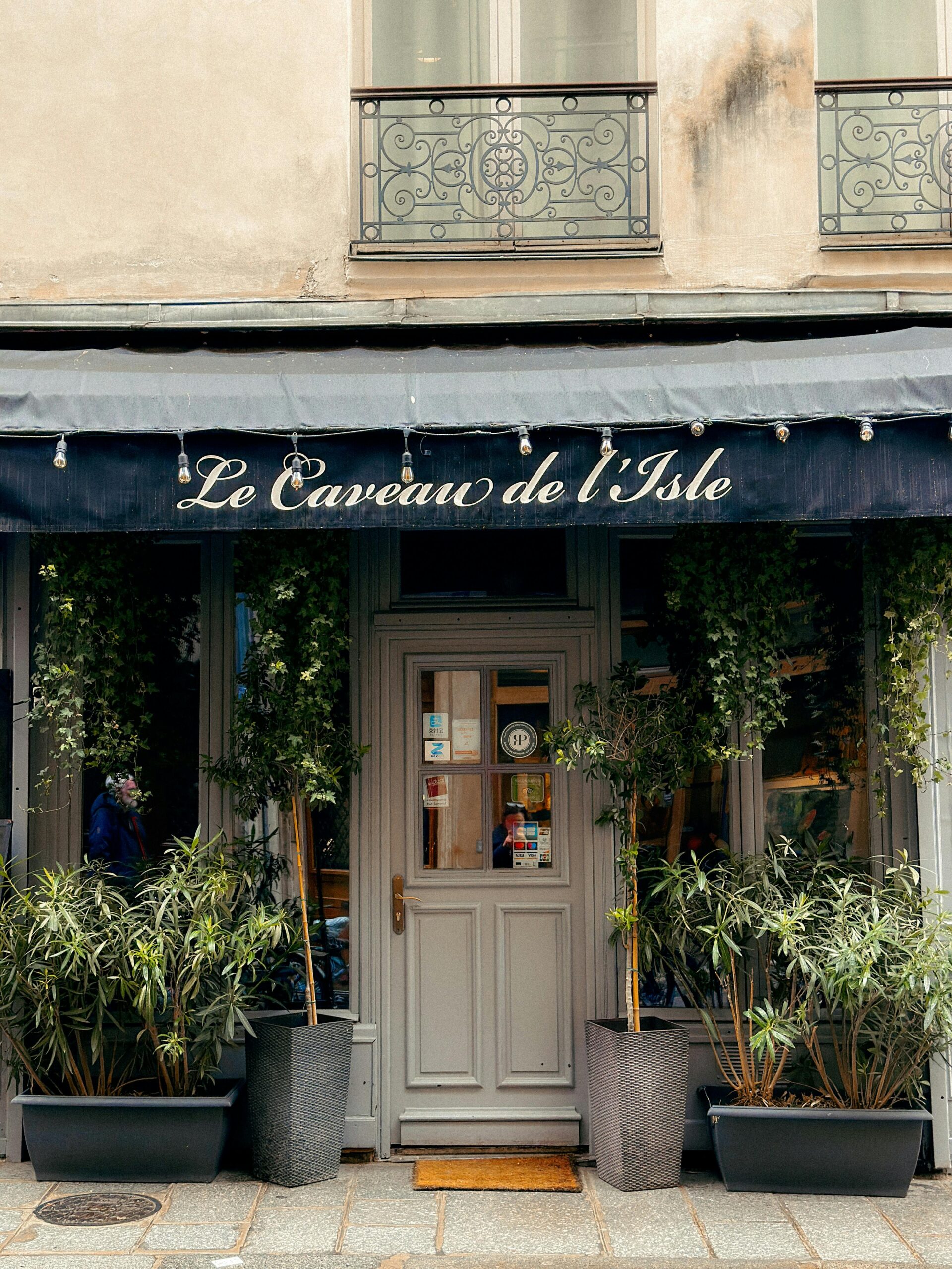 Elegant facade of Le Caveau de l'Isle in Paris, adorned with greenery.